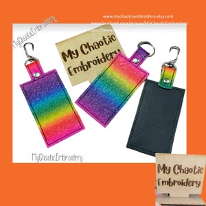 May include: Three keychains with different designs. The first keychain has a rainbow glitter design with a black border. The second keychain has a black leather design. The third keychain has a rainbow glitter design with a black border. All keychains have a silver metal ring and a silver metal hook.