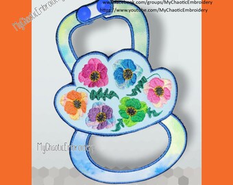 May include: A blue and white embroidered baby teether with a floral design. The teether has a loop for attaching to a stroller or car seat. The teether is made by MyChaoticEmbroidery.