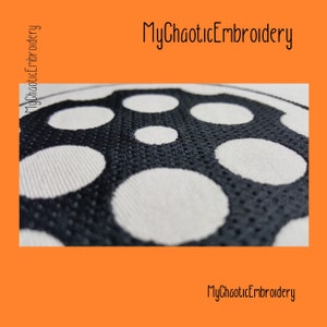 Puede incluir: Primer plano de un diseño bordado en blanco y negro con un patrón repetitivo de círculos. El diseño está sobre una tela blanca con una superficie texturizada. El texto "MyChaoticEmbroidery" es visible en la parte superior de la imagen.