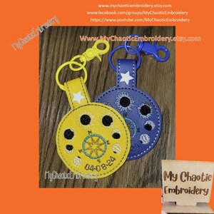 Puede incluir: Dos llaveros bordados. Uno es amarillo con un diseño de brújula y la fecha 04-08-24. El otro es azul con un diseño de estrella y sol. Ambos tienen un cierre y un anillo de metal. El texto "My Chaotic Embroidery" es visible.