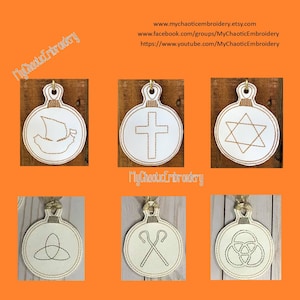 May include: Six white round ornaments with different religious symbols embroidered in brown thread. The symbols include a ship, a cross, a Star of David, a Celtic knot, a shepherd's crook, and a triquetra. The ornaments are on a wooden background.