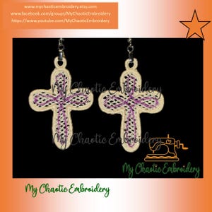Puede incluir: Un par de pendientes de cruz color crema con detalles bordados en morado. Las cruces cuelgan de ganchos plateados. La imagen incluye el texto "My Chaotic Embroidery" e información del sitio web.