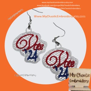 May include: A pair of silver earrings with red, white, and blue embroidered "Vote 24" designs. The earrings are hanging from a white background.