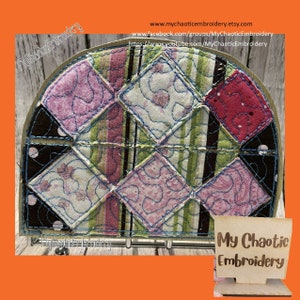 May include: A circular patchwork quilt with a variety of pink, green, and black fabrics. The quilt is stitched together in a diamond pattern and has a blue thread running through the seams. The quilt is displayed on a wooden stand with the text "My Chaotic Embroidery" on a sign.