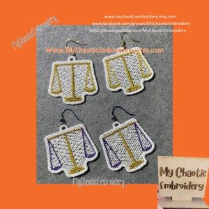 May include: Four embroidered earrings featuring a scales of justice design. Two pairs have gold and white embroidery, and the other two have purple and white embroidery. Each earring has a silver-colored hook.