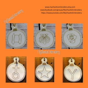 May include: Six white round ornaments with gold embroidery. The ornaments feature different religious symbols, including a cross, a star, a shell, a rose, a scroll, and a letter Y.
