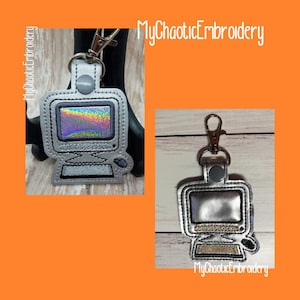 Puede incluir: Un llavero de ordenador plateado con una pantalla brillante. El llavero tiene un anillo de metal plateado y un cierre de metal plateado. El texto "MyChaoticEmbroidery" está impreso en el llavero.