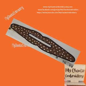 Puede incluir: Una pinza para el pelo marrón con un patrón de estrellas blancas. La pinza mide unos 10 cm de largo y tiene forma rectangular con una abertura central. El fondo es naranja con texto del vendedor.