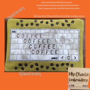 May include: A yellow fabric square with a white embroidered rectangle that says "COFFEE" four times. The rectangle is surrounded by a black stitched border. The fabric square is decorated with black embroidered coffee beans around the edges. A wooden sign with the text "My Chaotic Embroidery" is in the bottom right corner.