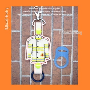 May include: A white firefighter jacket with yellow and red stripes is embroidered on a white fabric bottle holder. The bottle holder has a blue ring and a yellow ring. The bottle holder is attached to a blue and white bottle stopper. The text "MyChaoticEmbroidery" is visible in the image.