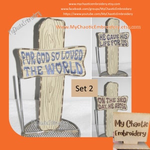 May include: Set of two wooden signs with embroidered Christian messages. The first sign reads "For God so loved the world". The second sign reads "He gave his life for us".