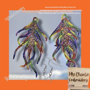 Può includere: Un paio di orecchini ricamati colorati a forma di stella marina o design astratto. Gli orecchini presentano un mix di colori arcobaleno e sono esposti con ganci argentati. Il nome del negozio Etsy "My Chaotic Embroidery" è visibile.
