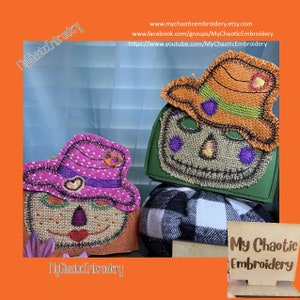 May include: Two burlap scarecrow faces with stitched details, one with a pink and white polka dot hat and the other with an orange hat. The scarecrows are on a green and white plaid background with a wooden sign that reads "My Chaotic Embroidery".