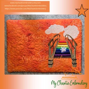 May include: Embroidered orange fabric with a rainbow bridge design. The bridge has brown supports and a rainbow archway. White clouds are above the bridge. The text "My Chaotic Embroidery" is embroidered on the fabric.