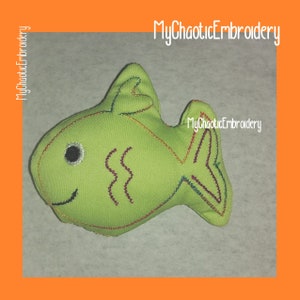 May include: A lime green fish-shaped soft toy with embroidered details. The fish features a smiling face, a black eye, and colourful stitching. The text "MyChaoticEmbroidery" is visible in the image.