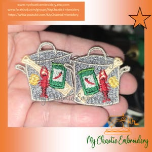 May include: Embroidered patch featuring two gray cooking pots with handles, each adorned with a red crawfish, a green and red chili pepper can, and a yellow lemon. The text "My Chaotic Embroidery" is visible.