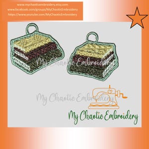 May include: Two embroidered cake slice charms with a green outline and a loop for hanging. The cake slices are layered with brown, yellow, and green fabric.