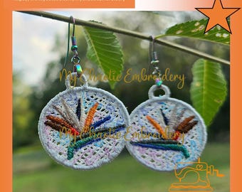Könnte beinhalten: Gestickte Ohrringe mit einem Paradiesvogel-Design. Die kreisförmigen Ohrringe haben einen weißen Hintergrund und farbenfrohe Stickereien in Orange, Blau, Grün und Braun. Die Ohrringe hängen an silberfarbenen Haken.