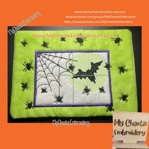 May include: A green and white embroidered patch with a black bat flying in front of a full moon and a spider web. The patch is surrounded by a purple border and has the text "My Chaotic Embroidery" on the bottom.