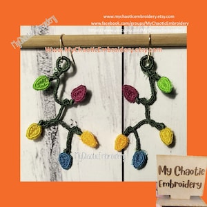 Puede incluir: Un par de pendientes hechos a mano con una cadena de luces de colores, cada luz es de un color diferente, incluyendo verde, amarillo, azul y morado. Los pendientes están hechos con hilo de bordar y están unidos a ganchos de pendientes de color dorado. Los pendientes se muestran en una varilla de madera. El texto "My Chaotic Embroidery" es visible en la imagen.