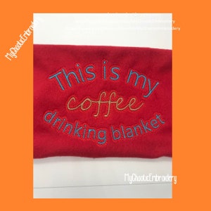 Könnte beinhalten: Rote Fleece-Decke mit gesticktem Text in Blau und Braun, der "This is my coffee drinking blanket" lautet.