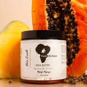 以下が含まれることがあります： 黒い蓋が付いた白い瓶で、ラベルには「Hair Crack Crack de Cheveux Hair Diction Shea Butter Beurre de Karité Mango Papaya Boz/226g」と書いてあります。瓶は白い表面に置かれており、隣にはパパイヤの半分とマンゴーがあります。