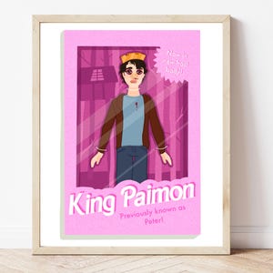 May include: A framed art print featuring a cartoon illustration of a figure in a doll box. The figure wears a crown, brown jacket, blue shirt, and jeans. Text reads "King Paimon" and "Now in new host body!" with "Previously known as Peter!"