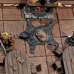 May include: A miniature tabletop gaming set with a brown wooden floor, a fireplace, a bear skin rug, and two tables with chairs. There are miniature figures of a warrior and a creature.