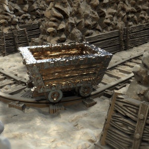 May include: A weathered, metallic mine cart with visible rust sits on a track. The cart is made of wood and metal, with four small wheels. The background features wooden fences and rocky formations, suggesting a mining environment.