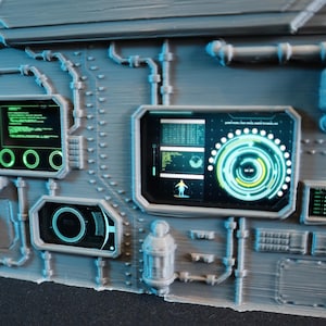 May include: A detailed, gray panel with multiple embedded screens and controls. The screens display green and blue graphics, including circular patterns and data readouts. The panel has a futuristic, technological aesthetic, with pipes and rivets.