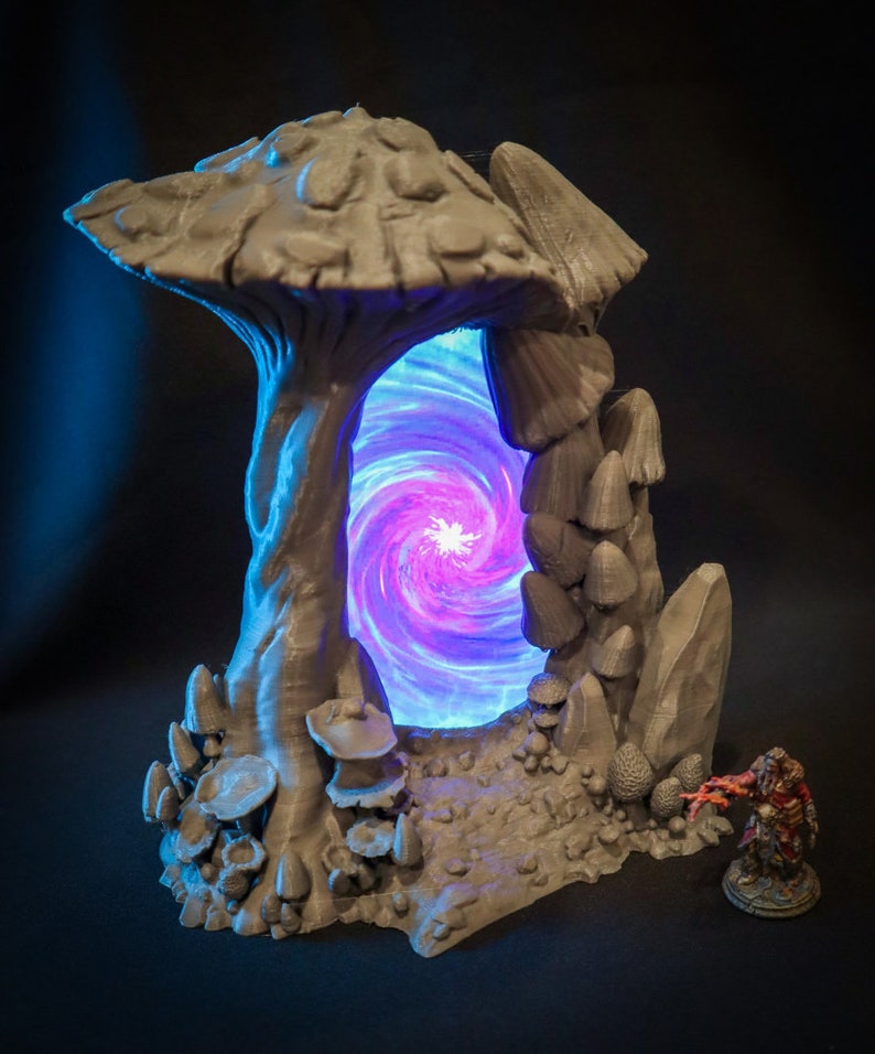 Peut inclure: Une miniature imprim&eacute;e en 3D d'un portail en forme de champignon avec une lumi&egrave;re bleue et violette tourbillonnante &eacute;manant du centre. Le portail est entour&eacute; de petits champignons et de rochers.