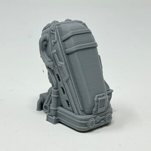 May include: A gray 3D printed model of a futuristic chair with a detailed design. The chair has a back, seat, and a base with wheels.