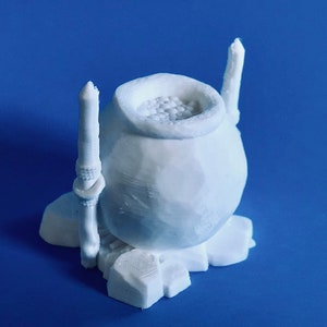 May include: White ceramic cauldron with a white base and two white candlesticks. The cauldron is filled with white beads.