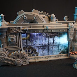 May include: A gray, steampunk-style, 3D printed miniature building with a window that shows a detailed, textured, industrial scene. The building has gears, pipes, and other mechanical details.