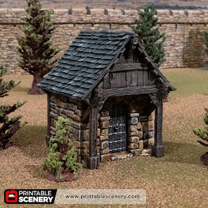 May include: A miniature stone building with a dark green shingled roof and a wooden frame. The building has a barred door and is surrounded by small trees and grass. The text "PRINTABLE SCENERY" and website address are visible.