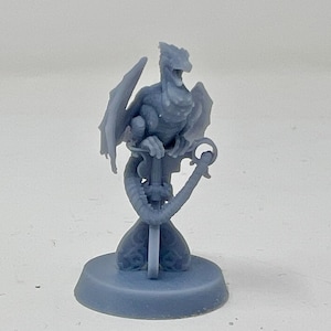 May include: A small, gray, 3D printed dragon figurine perched on a sword. The dragon has wings and a tail wrapped around the sword. The figurine is on a round base.