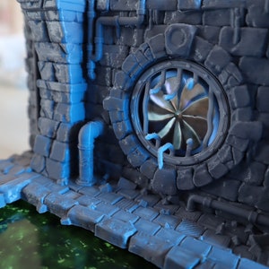 May include: A 3D printed model of a stone building with a large, round window featuring a metal fan. The building has a blue and gray color scheme and is set against a blurry background.