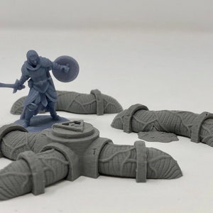 May include: A gray plastic miniature figure of a warrior holding a sword and shield standing on a gray plastic base with a triangular symbol. The base is connected to three gray plastic curved pieces.