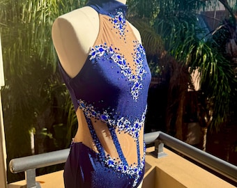 May include: A navy blue dance leotard with a high neckline and a sheer mesh panel. The leotard is decorated with blue and silver rhinestones in a floral pattern.