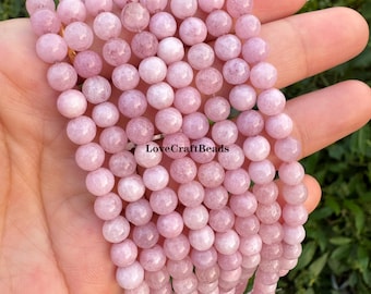 Puede incluir: Un hilo de cuentas lisas, redondas y de color rosa claro con una sutil textura veteada. Las cuentas están dispuestas en varias filas verticales, creando un aspecto uniforme. El texto LoveCraftBeads está impreso en negro sobre las cuentas.