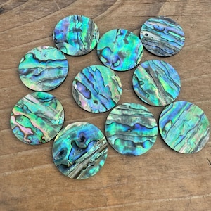 May include: Ten round iridescent abalone shell inlay circles with a green, blue, and purple color scheme.