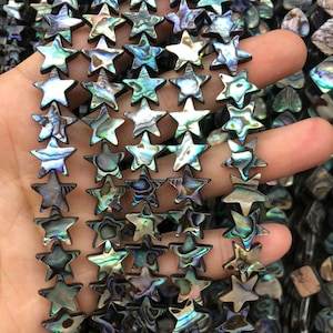 May include: A strand of iridescent abalone shell star-shaped beads. The beads are a mix of green, blue, and brown colors.