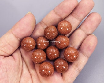May include: A collection of 12 smooth, round, red-brown sandstone beads. The beads are approximately 1 inch in diameter and have a natural, slightly rough texture.