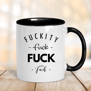 May include: White ceramic coffee mug with a black rim and handle. The mug has black text that reads "F*CKITY - f*ck - F*CK . f*ck ."