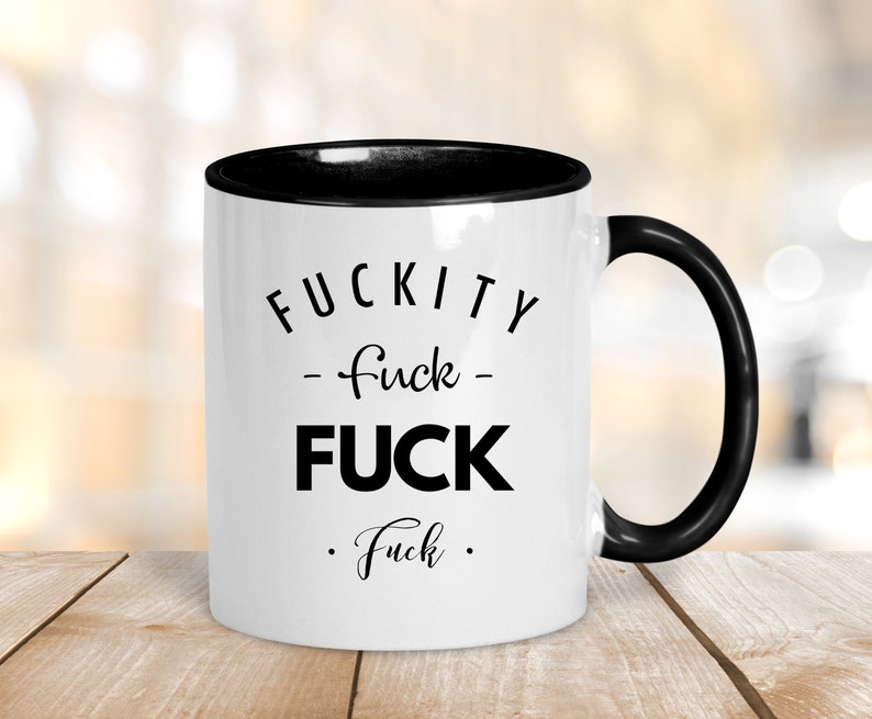 May include: White ceramic coffee mug with a black rim and handle. The mug has black text that reads "F*CKITY - f*ck - F*CK . f*ck ."