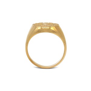 May include: A gold signet ring with a detailed design on the top.