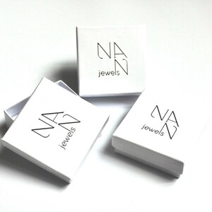 May include: Three white square boxes with the logo "NAN jewels" printed in black on the top of each box.