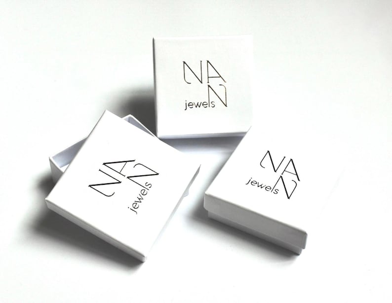 May include: Three white square boxes with the logo "NAN jewels" printed in black on the top of each box.
