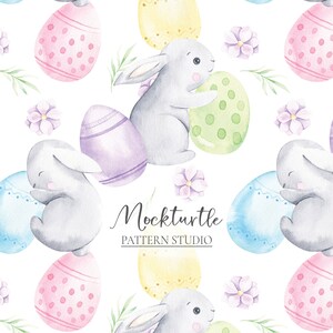 Könnte beinhalten: Ein nahtloses Muster mit Aquarell-Illustrationen von grauen Hasen, die bunte Ostereier halten. Die Eier sind mit Punkten, Streifen und Spiralen verziert. Der Hintergrund ist weiß mit kleinen lila Blüten.