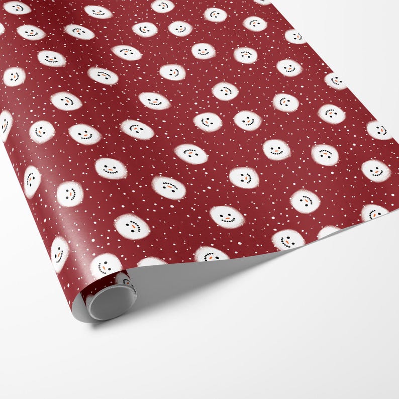 Puede incluir: Papel de regalo rojo con un patr&oacute;n repetido de mu&ntilde;ecos de nieve blancos con ojos y bocas negros. El fondo es rojo oscuro con puntos blancos.